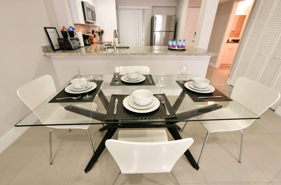 Glass dining table with four chairs beside the kitchen counter