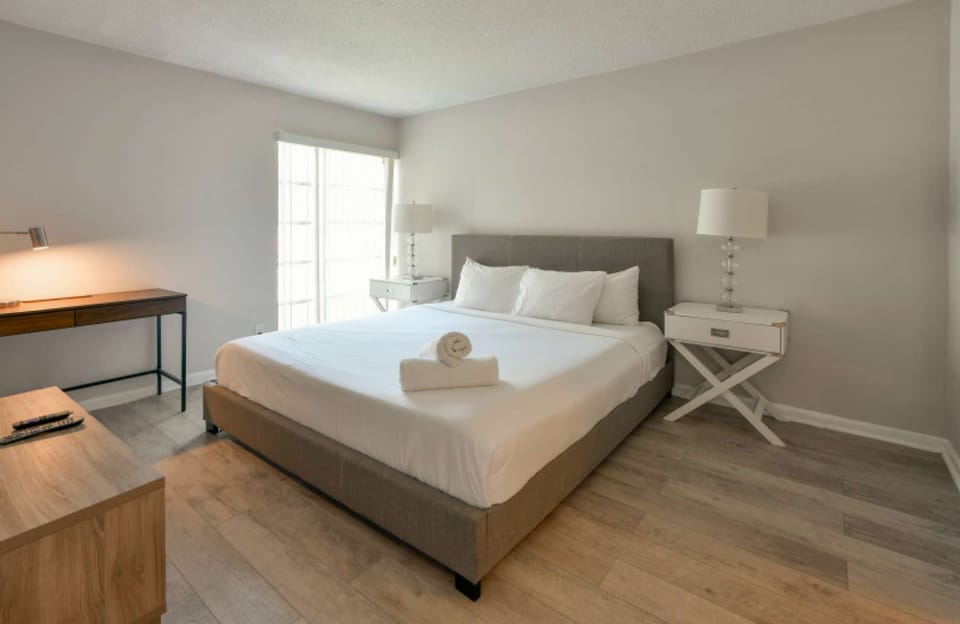 King bedroom with desk, side tables, lamps, and TV