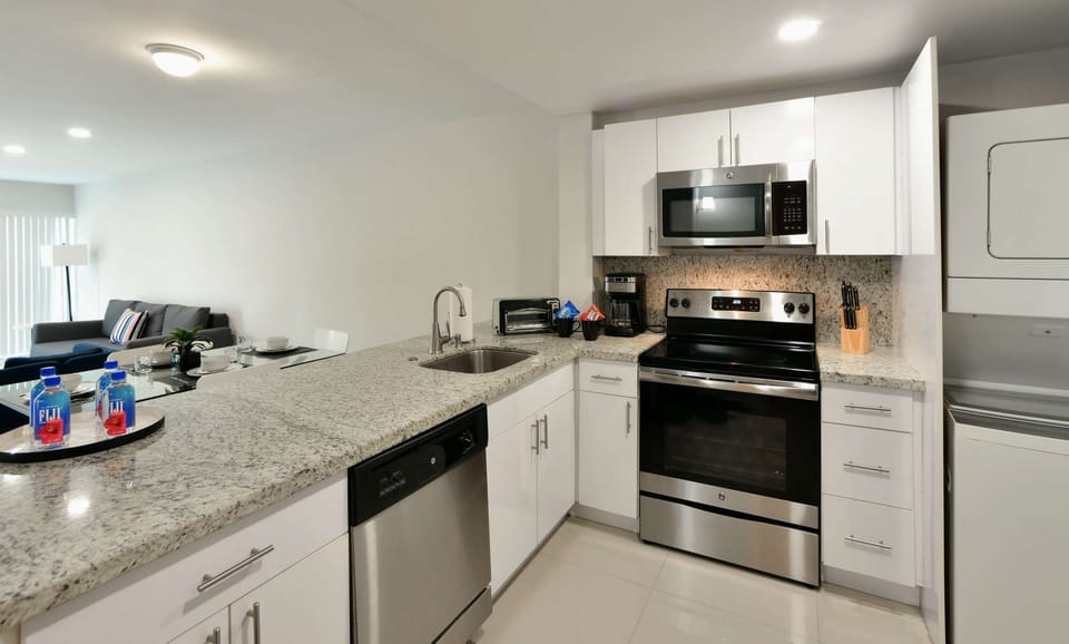 Bright kitchen with stove, sink, dishwasher, and white cabinets