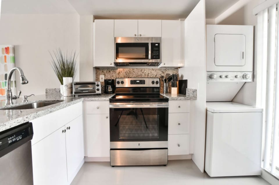 Bright kitchen with stove, sink, dishwasher, and stacked dryer