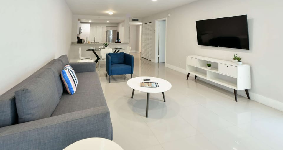 Open living room with sofa, chair, TV, and dining area