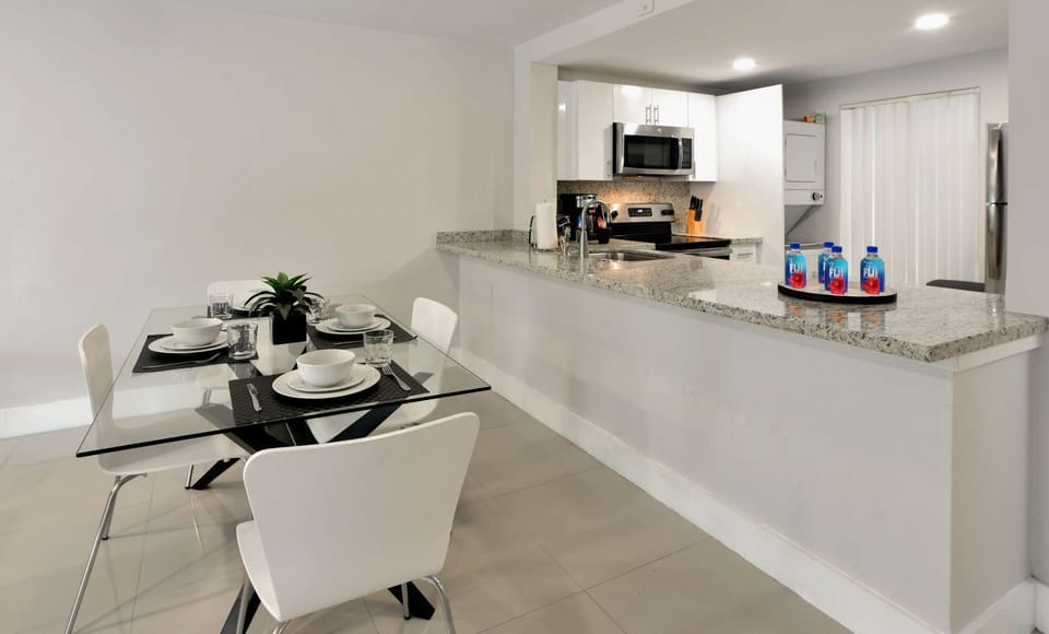 Glass dining table with four chairs beside the kitchen counter