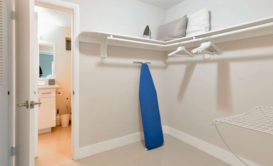 Walk-in closet with hangers, iron, shelf, and bathroom entry