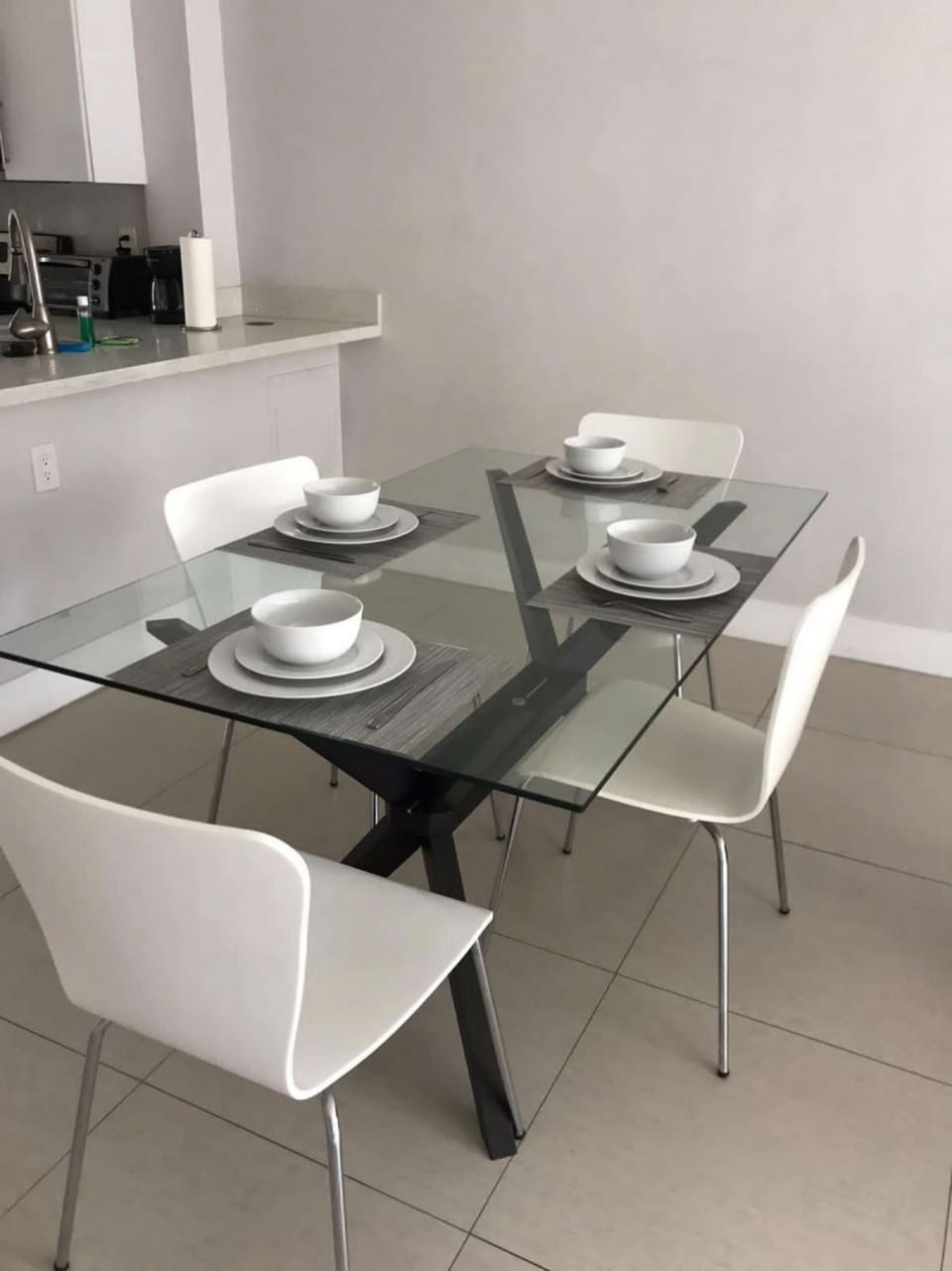 Glass dining table with four chairs beside the kitchen counter
