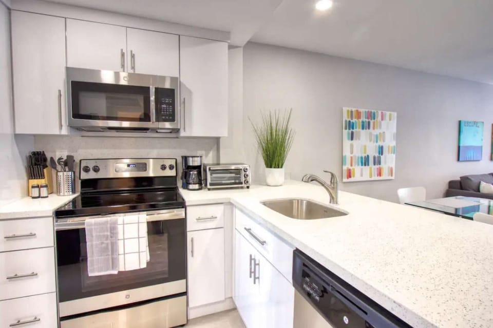 Bright kitchen with stove, sink, counter, and wall art