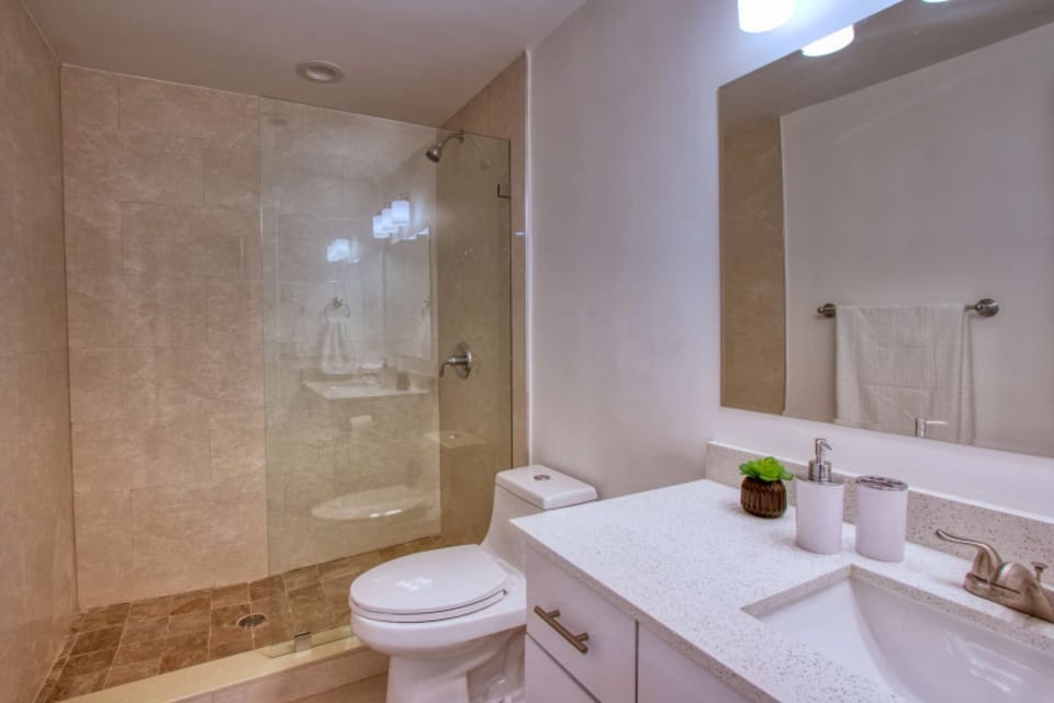 Clean bathroom with sink, toilet, mirror, and glass shower