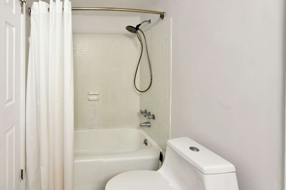 Simple bathroom with tub, shower curtain, and toilet
