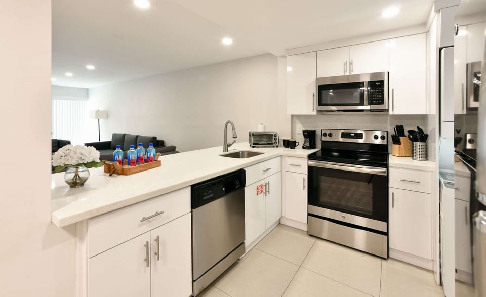White kitchen with stove, sink, dishwasher, and counter