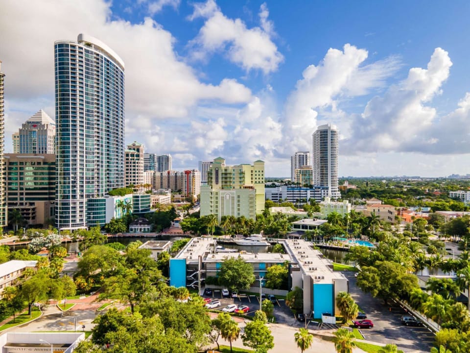 City view with tall buildings, trees, streets, and bright clouds