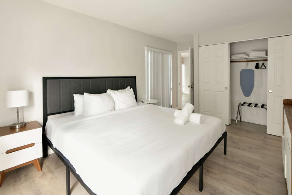 Bright king bedroom with open closet, side table, and lamp
