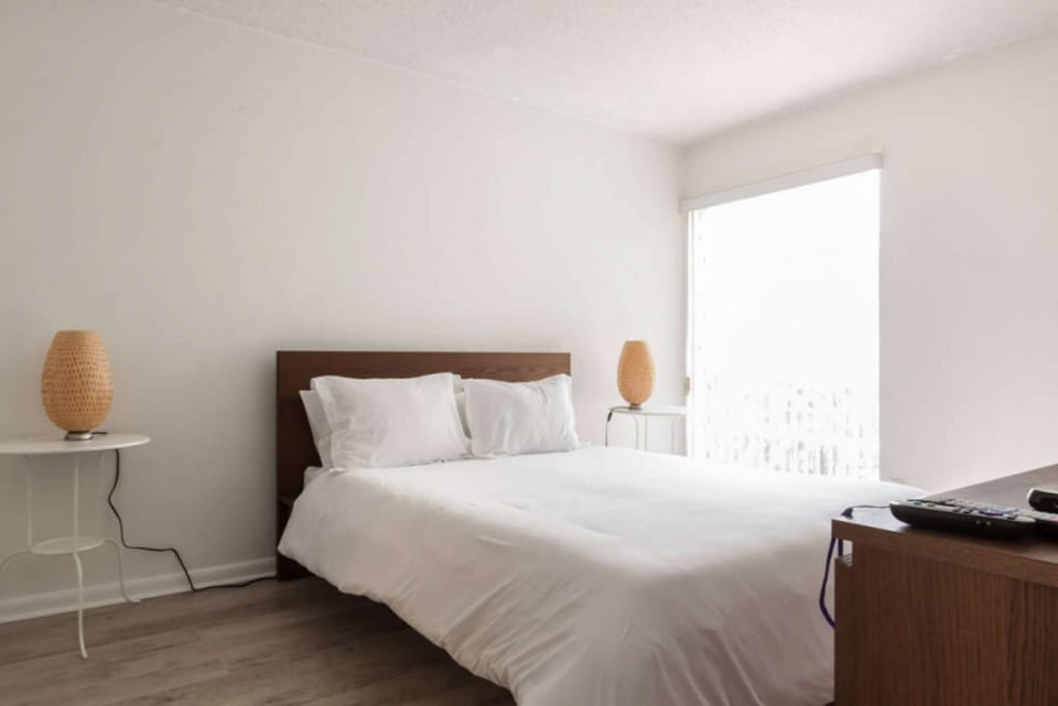 Bedroom with white bed, side lamps, and wood dresser