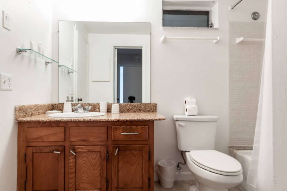 Clean bathroom with wood vanity, mirror, toilet, and shower tub