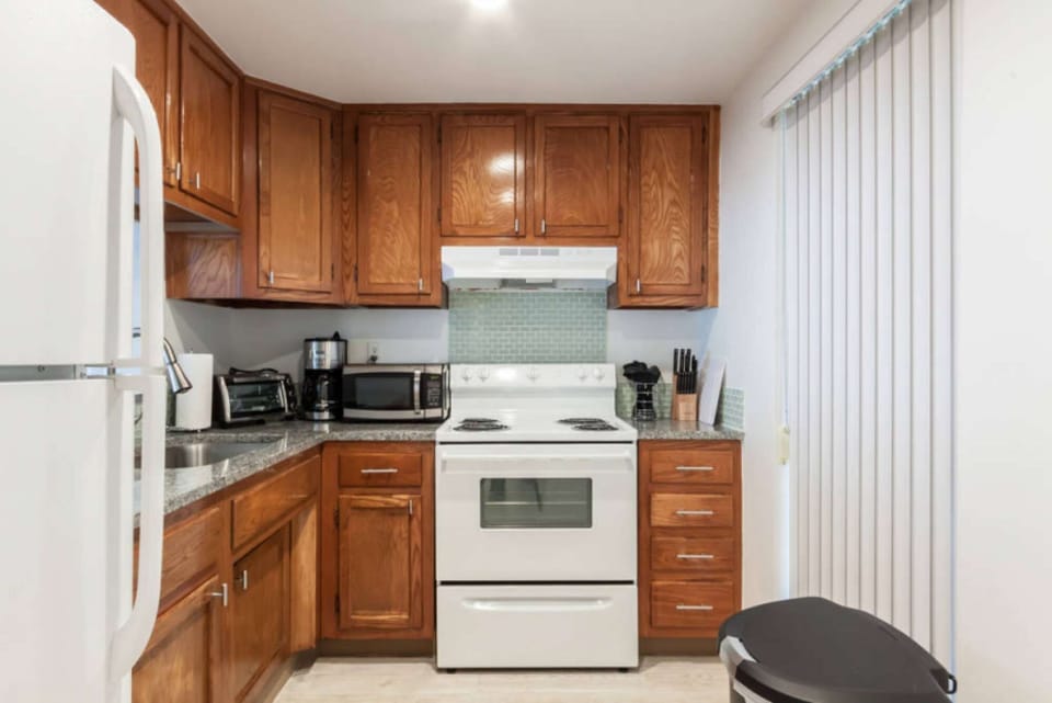 Kitchen with wood cabinets, stove, sink, and coffee maker