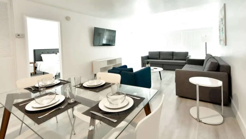 Open dining and living area with sofa, chairs, TV, and table