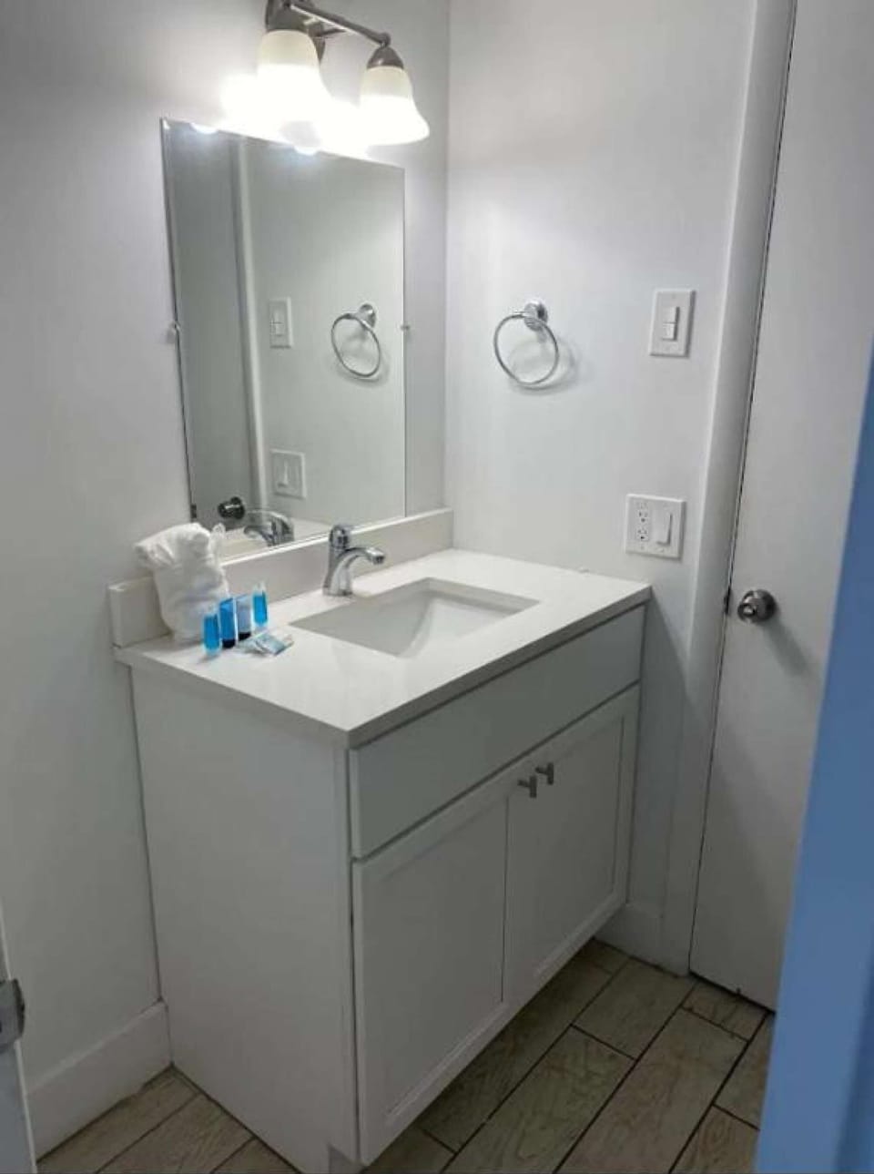 Clean bathroom sink with mirror, lights, and fresh toiletries