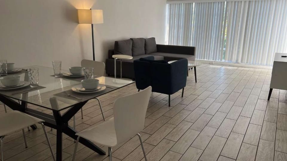 Open dining and living area with sofa, chairs, and tall windows