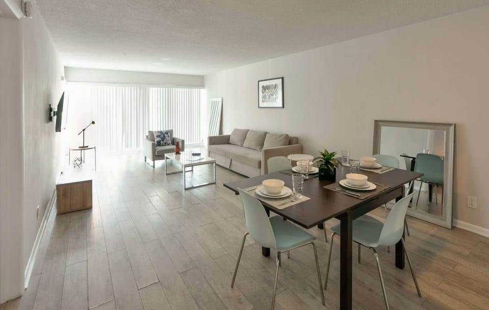 Bright living and dining space with sofa, chairs, and wide window