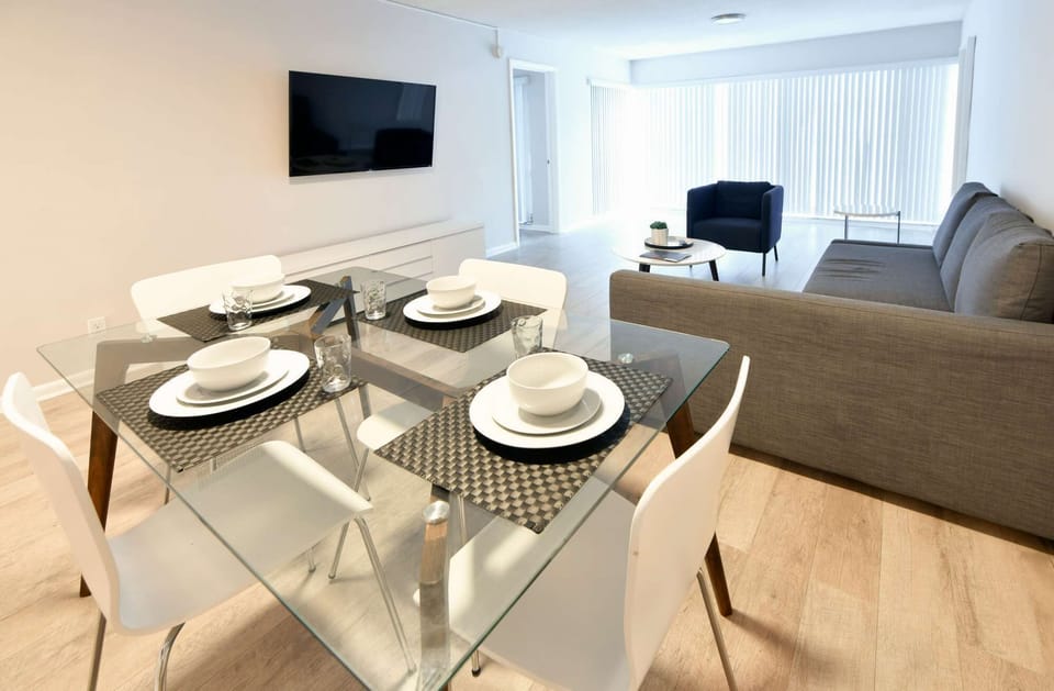 Dining area with table, chairs, sofa, TV, and bright windows