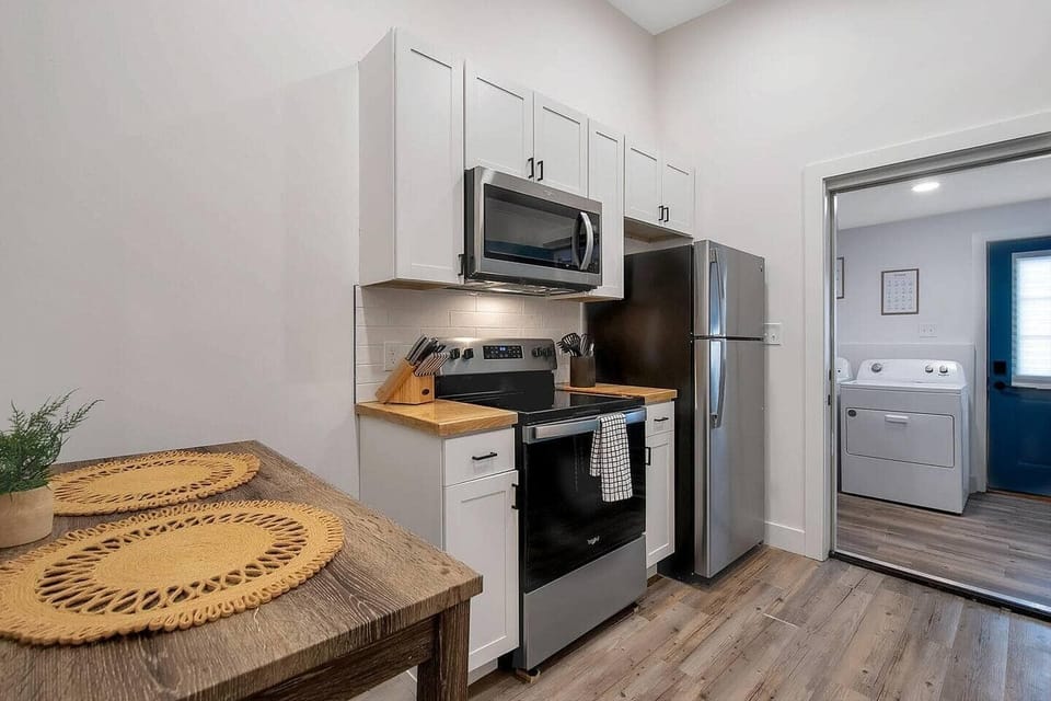 Kitchen with small dining area, butcher block countertop, stainless steel appliances - opens into the laundry room. 