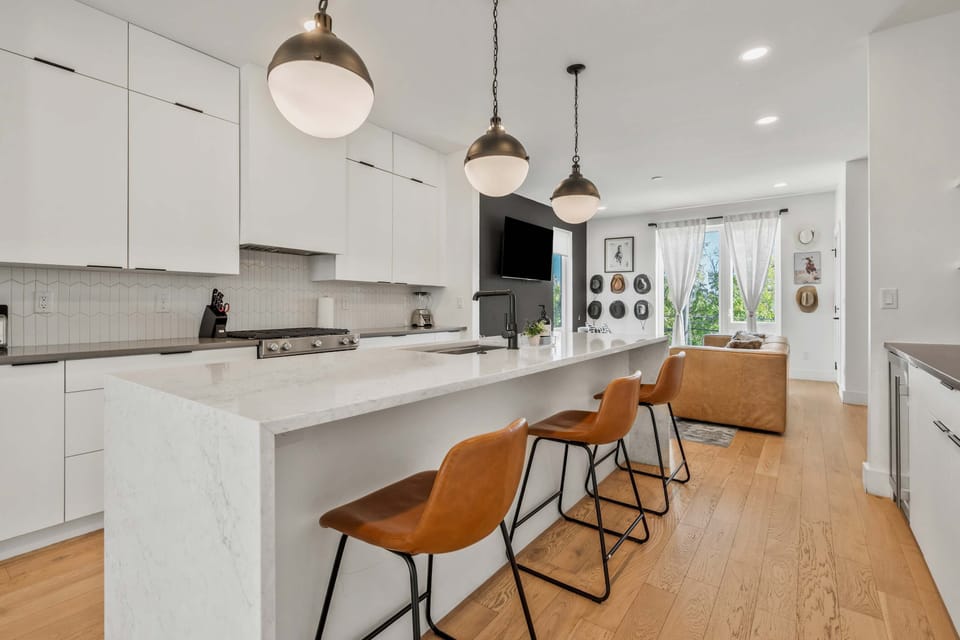 Sleek all-white kitchen with island counter for casual dining.