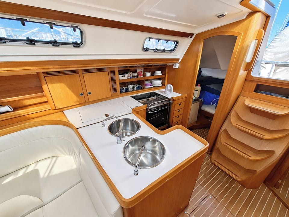 Bright compact bathroom with a marine toilet, washbasin, storage and overhead hatch.
