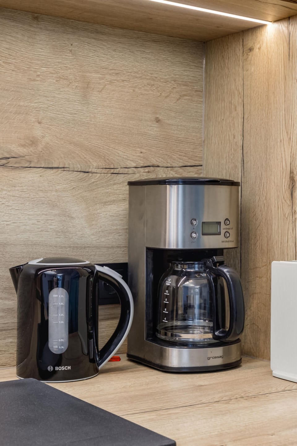 A kitchen corner showcasing a coffee maker and kettle on a light wooden counter.
