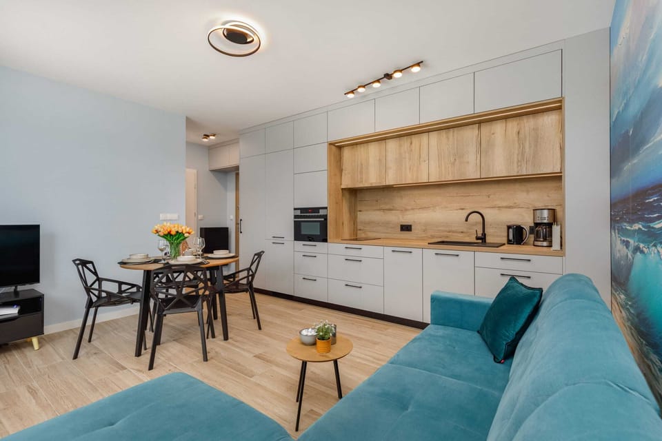 Open kitchen and living room with wooden cabinetry and a turquoise sofa.
