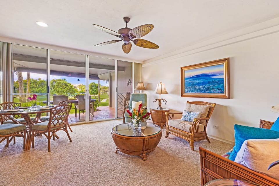 This spacious open-concept living room connects seamlessly to the outdoor lanai, creating the perfect setting for indoor-outdoor living with panoramic tropical views and a relaxed ambiance.