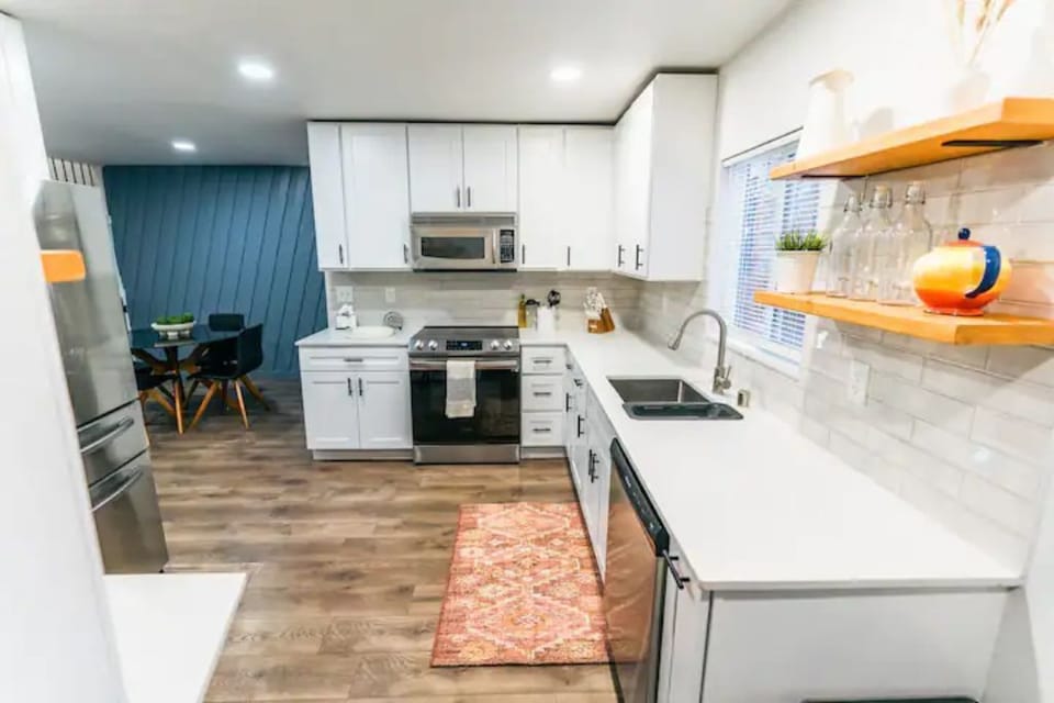 The bright white kitchen with brand new stainless steel appliances. 