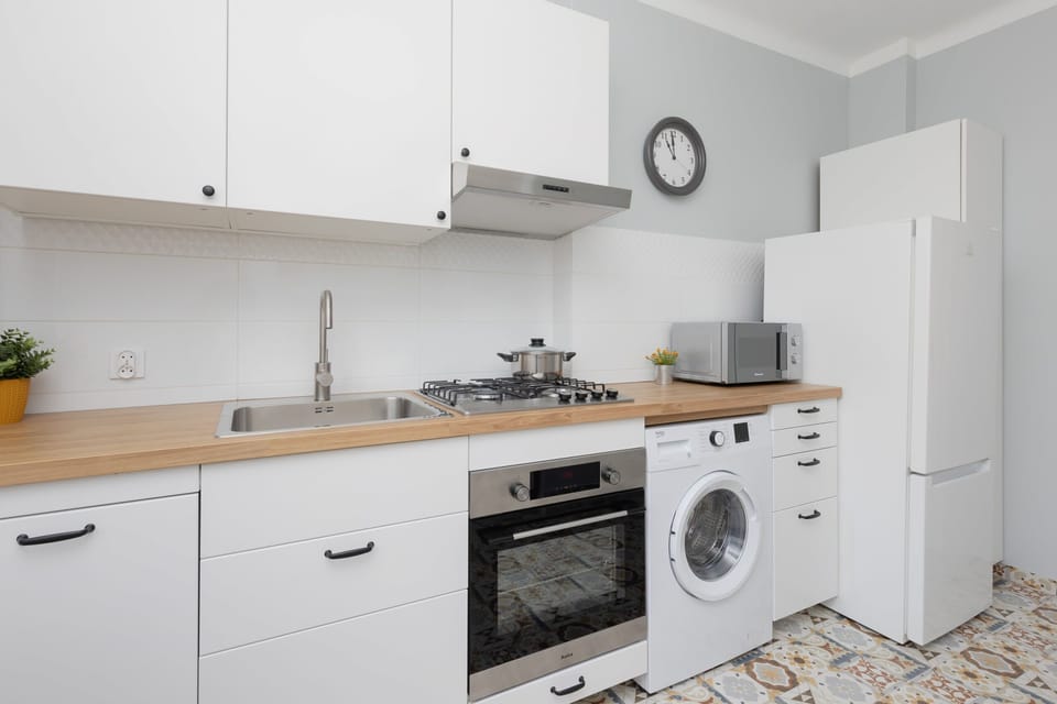 Modern kitchen equipped with a washing machine, white cabinetry, and patterned tile flooring.

