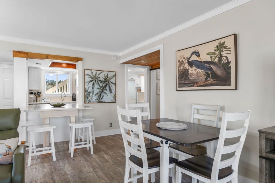 Step into a bright, coastal-inspired space where your dining and kitchen areas blend seamlessly. Natural light pours in, highlighting the clean lines and inviting breakfast bar—perfect for your morning coffee or evening gatherings.