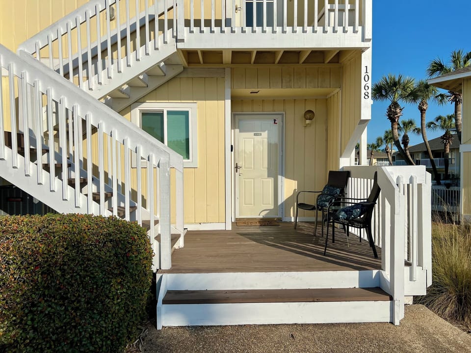 Beach cottage entrance with palm trees and coastal charm welcoming your arrival.