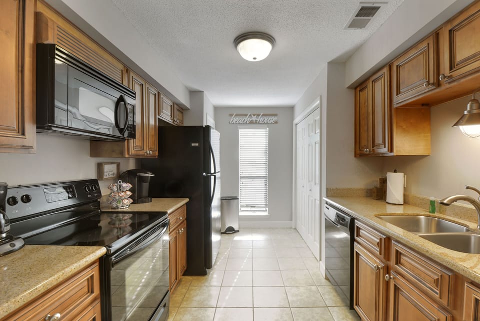 Galley Kitchen Toward Back Door - Kitchen includes full-size appliances, sink, counter space, and the back door at the far end.