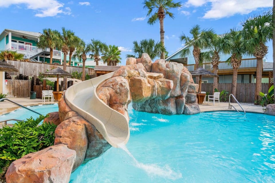 Community pool with waterslide and palm tree views.