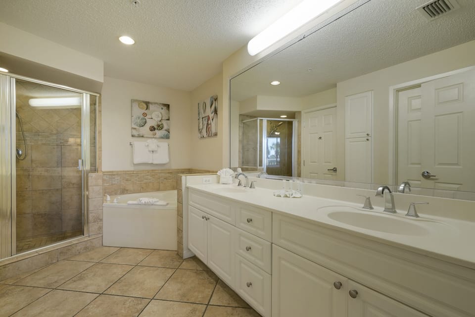 Featuring a double vanity, soaking tub, and walk in shower, this Destin beachfront condo offers the space families need to get ready with ease.