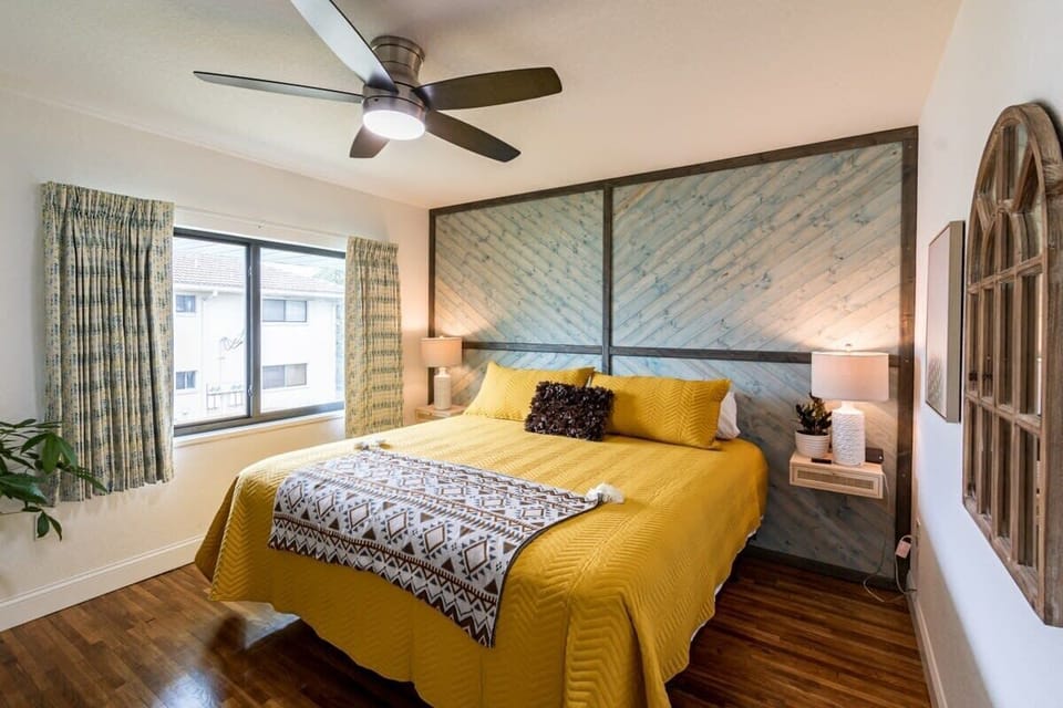Cozy bedroom featuring a king-size bed with a yellow quilt and a rustic wood accent wall.