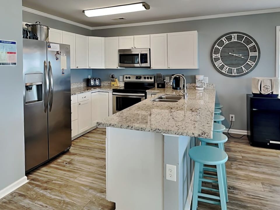Fully Equipped Kitchen with Stainless Steel Appliances and Breakfast Bar Seating for Four