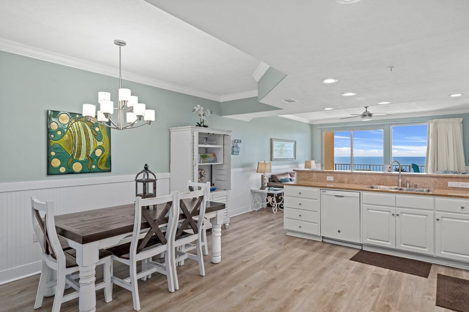 Open dining and kitchen area with ocean views and coastal decor.