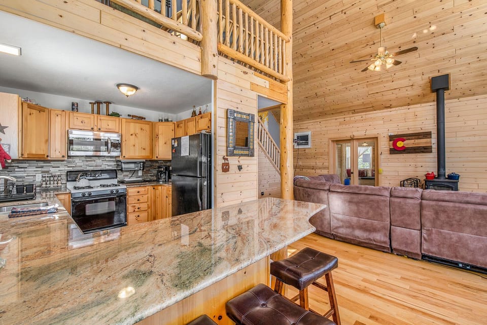  Granite countertops lead into a spacious lounge with high ceilings and soft lighting
