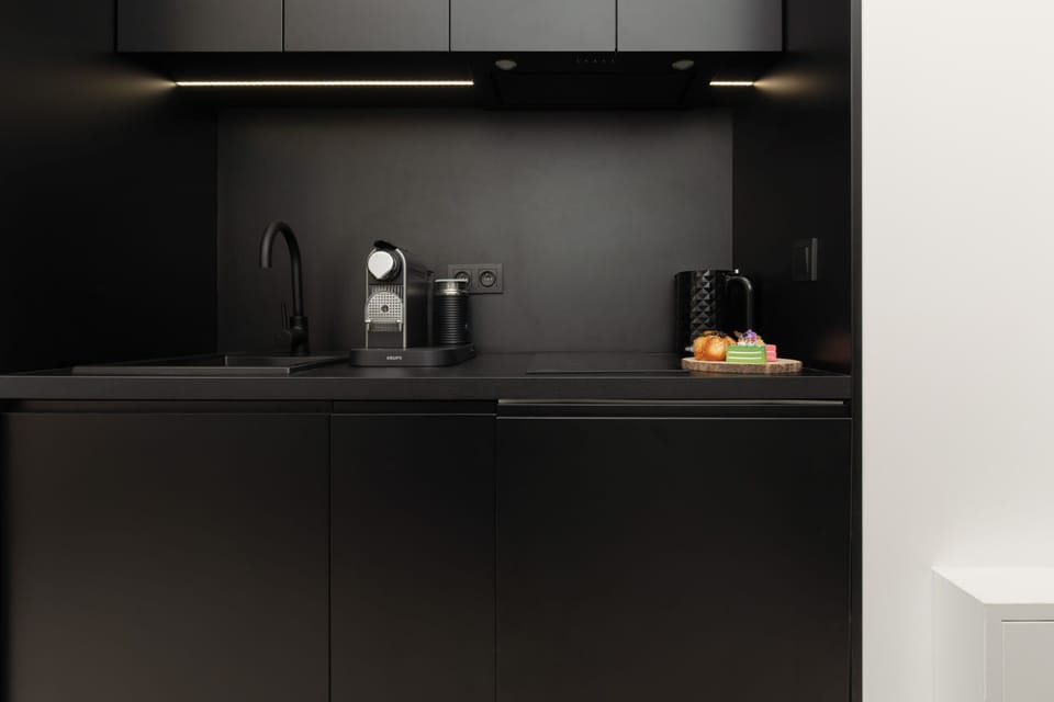 A compact yet fully equipped black kitchen with modern appliances and a minimalist aesthetic.

