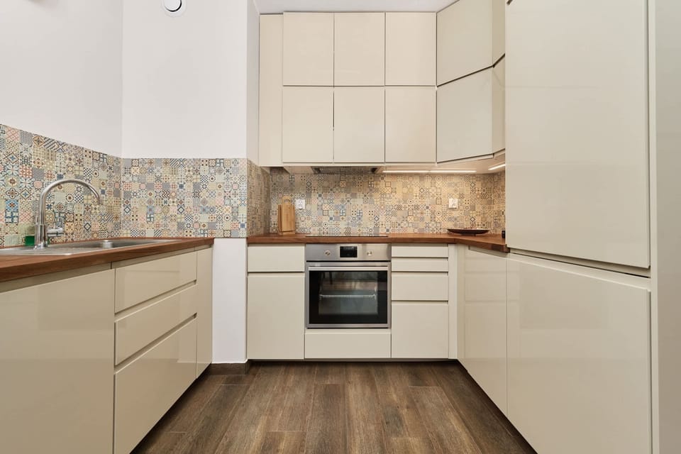 Fully equipped kitchen with sleek cabinets, a built-in oven, and a backsplash of patterned tiles.

