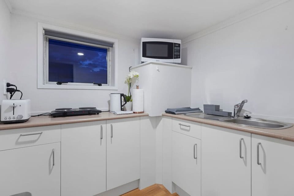 The kitchen is a half-kitchen with a microwave and hotplate with two elements rather than a full oven. There are normal small appliances like a toaster and jug.