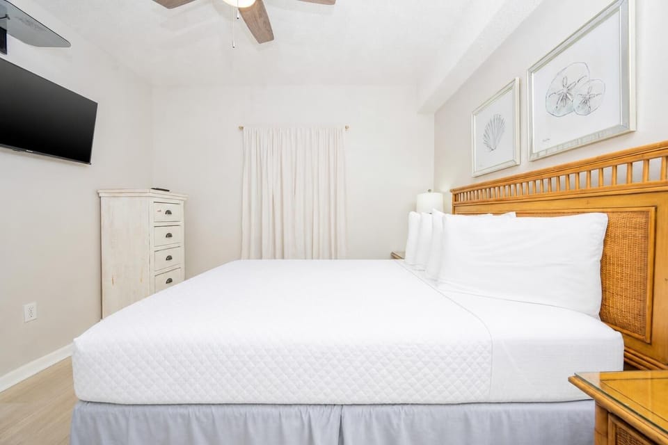 Relax in this inviting guest room featuring a queen bed, soft linens, and coastal artwork that enhances your comfort