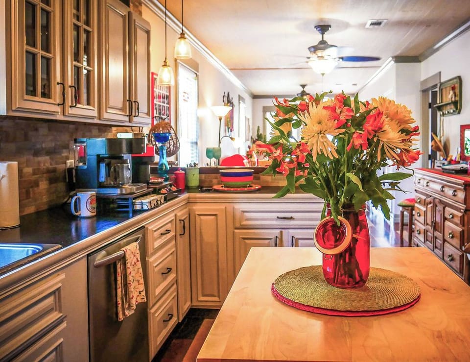 Fully equipped chef's kitchen with butcher block island, modern appliances, and colorful vintage accents in historic home