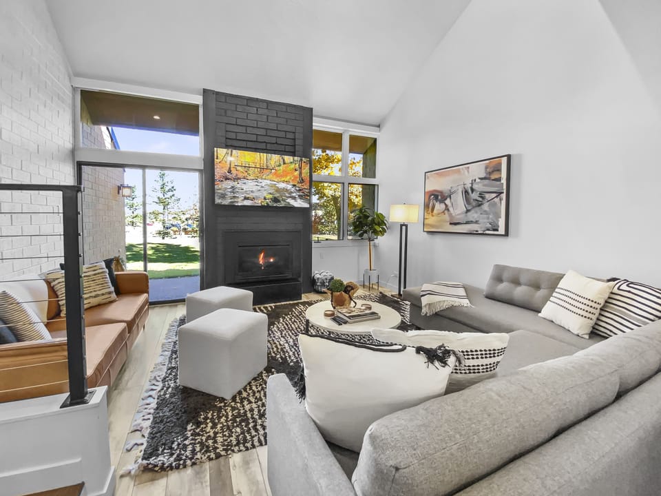 Relax in this cozy, modern living space. Features a warm fireplace, comfortable seating, and access to a patio. Perfect for unwinding.