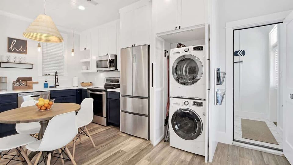 - Sleek stainless appliances, navy lowers, and white uppers create a fresh and stylish kitchen - Stackable washer and dryer are perfectly tucked away for convenience - Round wood table offers a cozy space for coffee, snacks, or quick meals