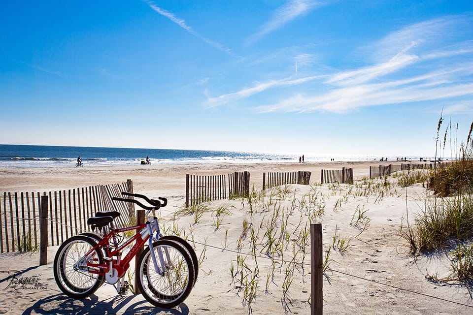 Scenic beachside with bikes, sand dunes, and ocean views under a bright blue sky.