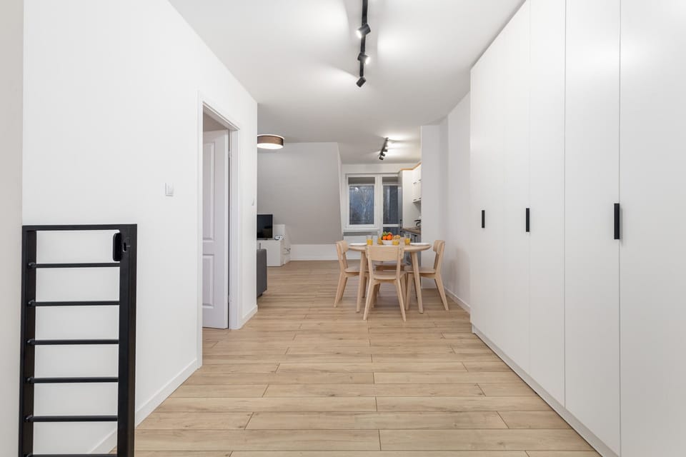 A hallway view with bright lighting and a modern, minimalistic design leading to the dining area.

