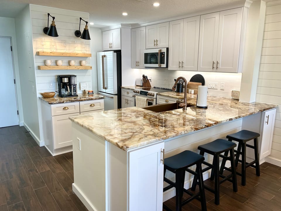 Broad view of kitchen with 3 bar stools for casual dining & snacks.