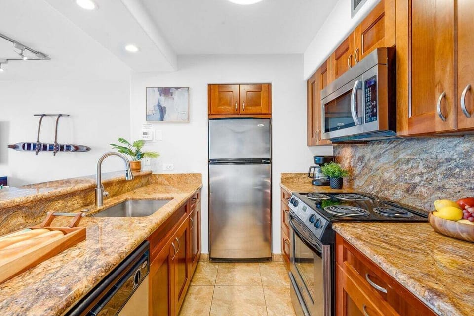 Modern kitchen featuring granite countertops, stainless steel appliances, and warm wood cabinetry